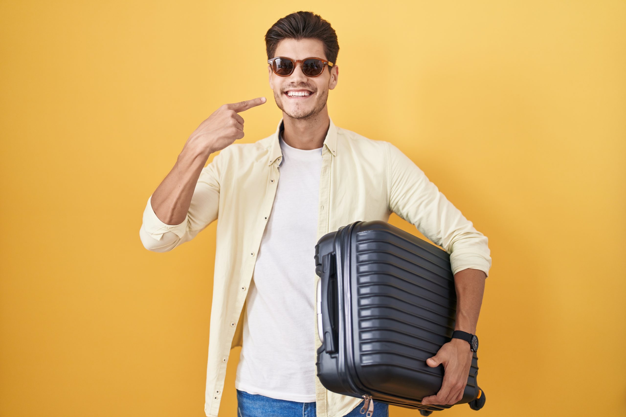 Young,Hispanic,Man,Holding,Suitcase,Going,On,Summer,Vacation,Smiling